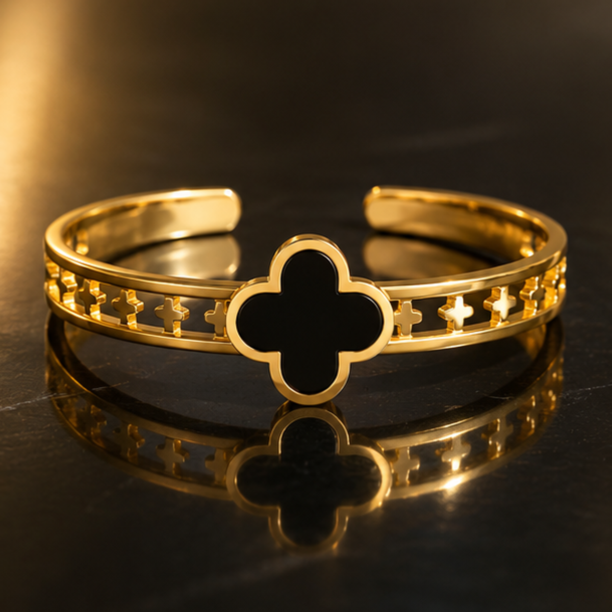 Delicate gold tone open bangle featuring a black clover design and refined finish by Maelle