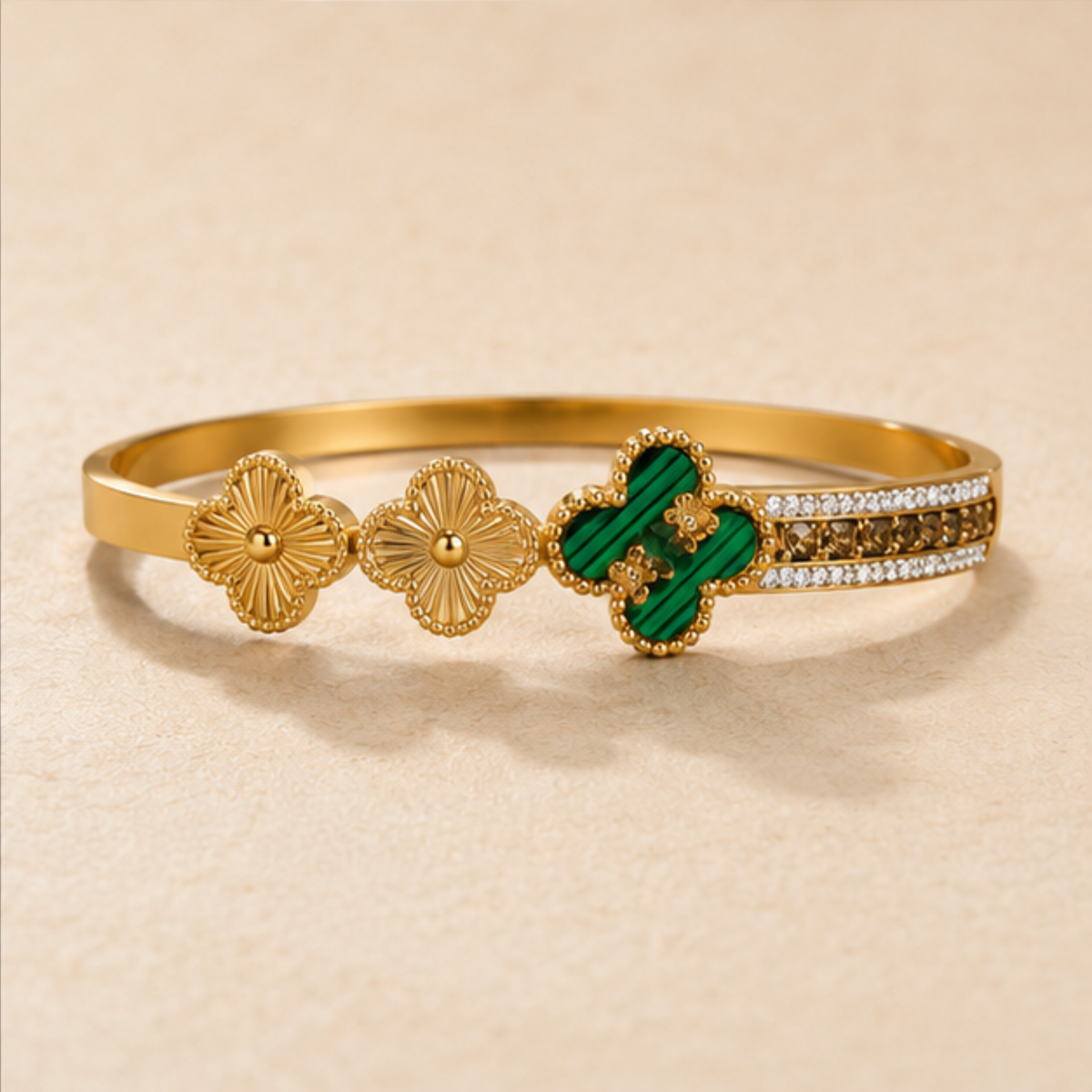 Delicate gold floral bangle with green clover accents and sparkling details designed for everyday elegance by Maelle