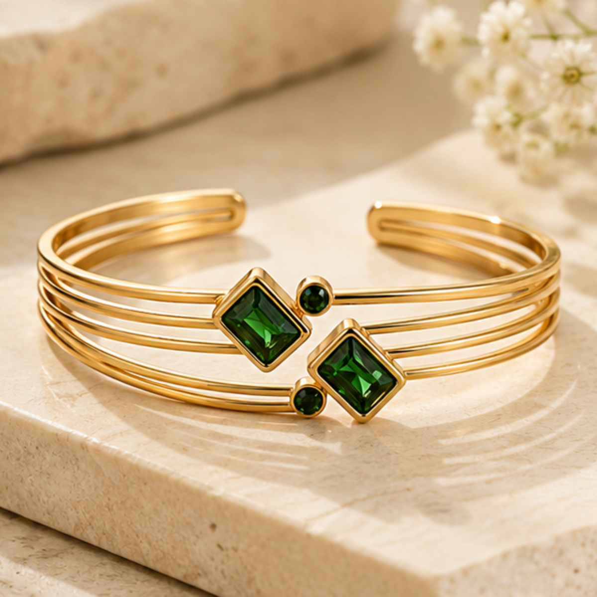 Delicate gold tone open bangle featuring a green square accent and refined finish by Maelle