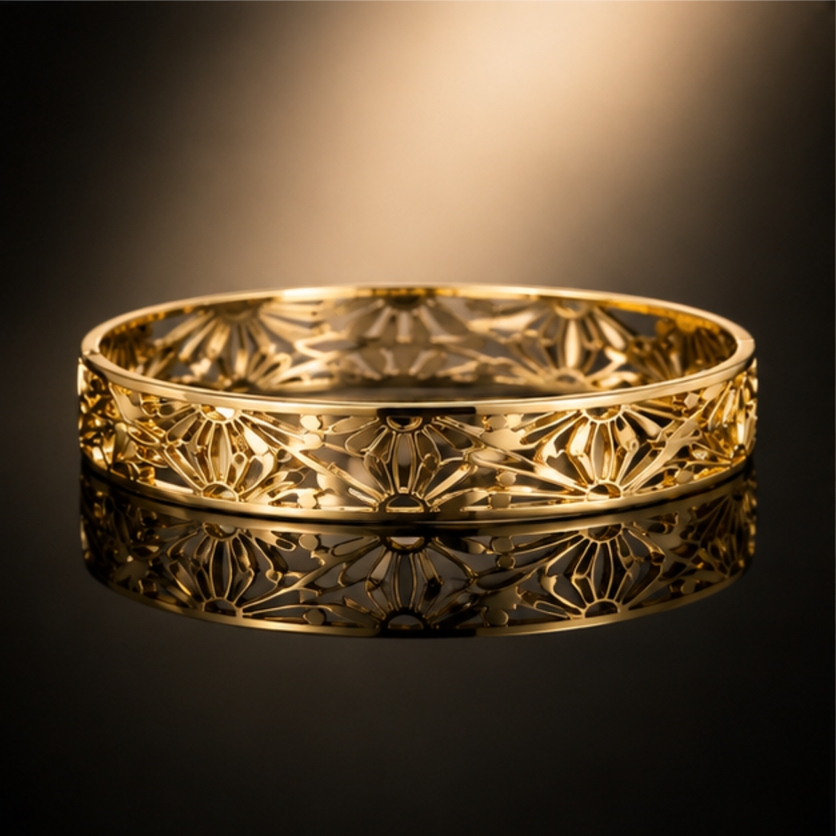 Delicate gold tone bangle bracelet featuring an openwork pattern and refined finish by Maelle