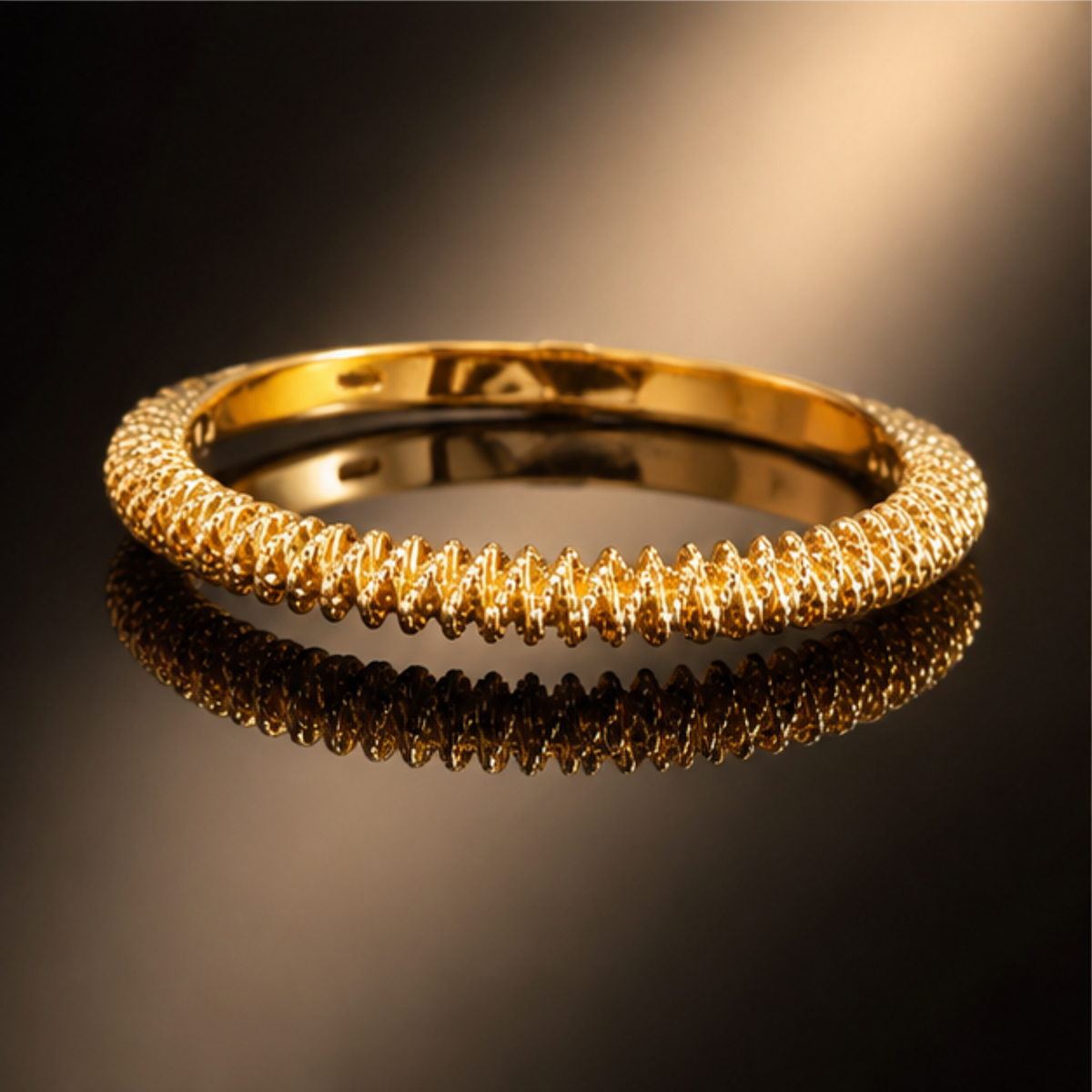 Delicate gold tone bangle bracelet featuring subtle textured detailing and a polished finish by Maelle
