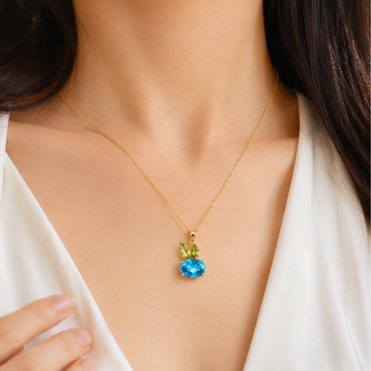 Elegant gold tone necklace with a blue crystal pendant and delicate chain by Maelle