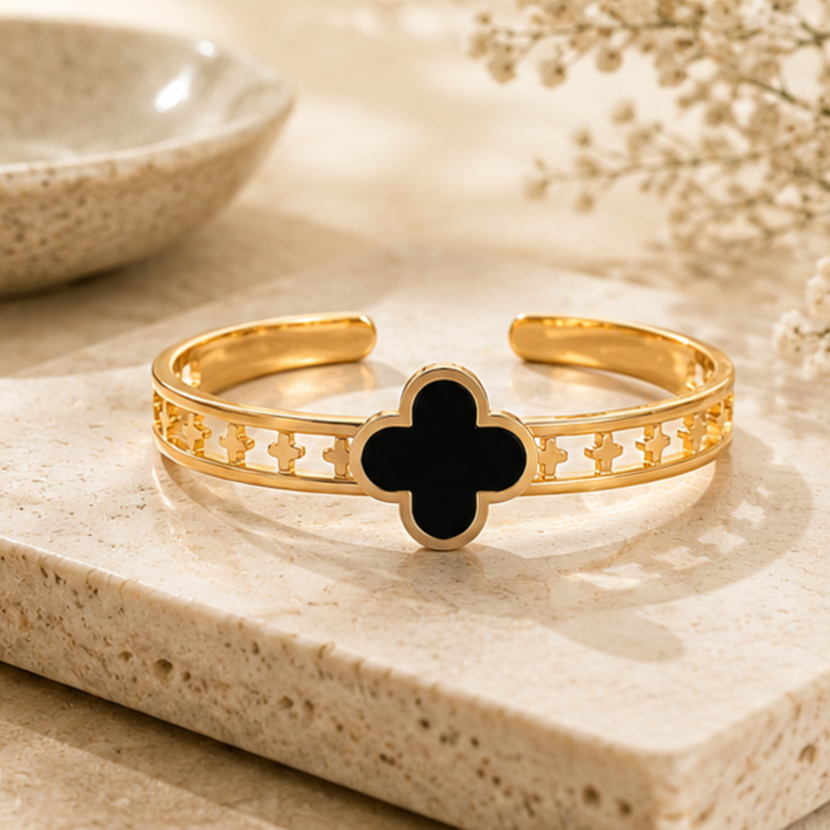 Gold tone open cuff bracelet with black clover detailing designed for everyday elegance by Maelle